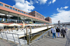 Neubauten in der Hamburger Hafencity - Elbarkaden am Magdeburger Hafen / Aussengastronomie mit Sonnenschirmen am Wasser; Anleger Maritimes Museum für Fahrgastschiffe.