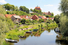 Blick über den Stadtgraben in der Hansestadt Havelberg - Holzkähne am Ufer; Häuser mit Gärten am Wasser; im Hintergrund der Havelberger Dom St. Marien.