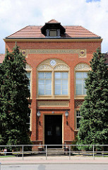 Schulgebäude, Eingang - Fassadenschmuck, Wappen von Perleberg; Inschrift DER VOLKSBILDUNG ERRICHTET. OHNE FLEISS KEINE PREIS.