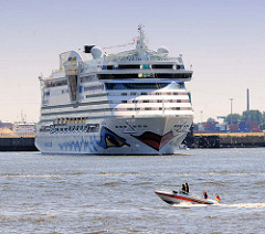 Das Kreuzfahrtschiff AIDAluna wendet im Hamburg Hafen - im Hintergrund Steinwerder; ein kleines Sportboot in Fahrt auf der Elbe.