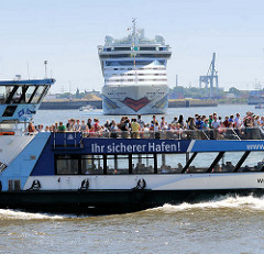 Das Kreuzfahrtschiff AIDAluna wendet im Hamburg Hafen - eine vollbesetzte Hafenfähre fährt vorüber; Aufschrift Ihr sicherer Hafen.