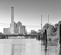 Moorfleeter Kanal in Hamburg Billbrook; rostige Dalben am Kanalufer - im Hintergrund das Kraftwerk Tiefstack mit Schornsteinen.