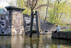 Altes Brückenfundament am Ufer des Tiefstackkanals in Hamburg Billbrook - ein Angler sitzt am Ufer.