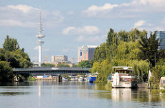 Sportboote liegen am Ufer der Schrebergärten des Bullenhuser Kanals in Hamburg Rothenburgsort - im Hintergrund die Brücke vom Ausschläger Billdeich und der Hamburger Fernsehturm.