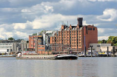 Ein Binnenschiff läuft von der Norderelbe in die Billwerder Bucht ein - im Hintergrund das historische Speichergebäude und Industrieanlagen am Ausschläger Elbdeich.