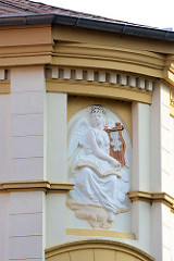 Bauschmuck an einem Gründerzeitgebäude - Figur mit Flügeln / Engel mit Harfe.