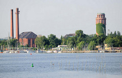 Blick über den Plauer See zum Industriegebiet des Ortsteil Kirchmöser / Brandburg a. d. Havel. Hohe Fabrikschornsteine - Wasserturm; Marina am Ufer des Sees.