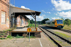 Einfahrt eines Nahverkehrszugs am Bahnhof Neustadt Glewe; das Bahnhofsgebäude ist stillgelegt; Rampe des Güterbahnhofs - Schild Zutritt verboten.