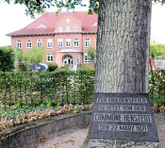 Friedenseiche an der Dorfstrasse von Henstedt / Henstedt-Ulzburg, im Hintergrund das Schulgebäude. Inschift des Gedenksteins: Zur Friedensfeier Gesetzt von der COMMUNE HESTEDT den 22. März 1871.