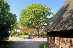 Dach einer Strohdachkate / Reetdach - Blick zur Friedenseiche und Schule an der Dorfstrasse im Ortsteil Henstedt in Henstedt-Ulzburg