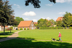 Grünanlage bei der alten Burg von Neustadt-Glewe; Spaziergänger mit Hund an der Leine.