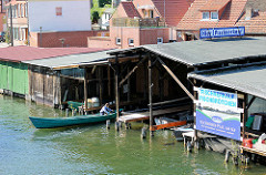 Bootshäuser in Plau am See - ein Fischer legt mit seinem Boot im Bootshaus an.