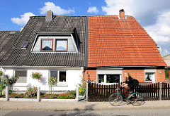 Doppelhäuser unterschiedliche Fassadengestaltung und eingedeckte Dächer; Fahrradfahrerin.