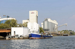 Silos auf einem Arbeitsboot und am Ufer der Rethe in Hamburg Wilhelmsburg; Entsorgungsschiff DON MULI.