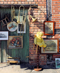 Trödelladen in der Schweriner Strasse von Neustadt Glewe; Bilderrahmen und Musikinstrumente an der Ziegelwand.