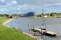 Hafen von Friedrichskoog / Dithmarschen. Ein Segelboot liegt am Steg. Im Hintergrund die Architektur vom Wal-Gebäude, das einen Indoorspielplatz beinhaltet.