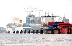 Blick über die Norderelbe zum Kreuzfahrtterminal Hafencity. An den Dalben im Fluss haben Auflieger festgemacht.