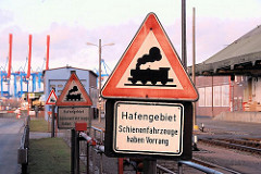Schild Hafengebiet, Schienenfahrzeuge haben Vorrang - im Hintergrund die hochgefahrenen Ausleger der Containerkräne auf der anderen Seite der Süderelbe in Hamburg Altenwerder.