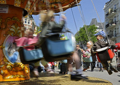 Kinderkarussell auf dem Strassenfest - Kinder haben Spass im drehenden Kettenkarussell am Strassenrand der Hamburger Osterstrasse.