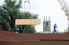 Verladung von Stückgut am Wilhelsburger Reiherstieg - mit dem bordeigenen Kran wird ein Stapel Holzbretter an Bord gehievt.