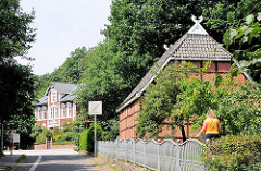 Fachwerkhaus mit Ziegeldach - im Hintergrund ein Wohnhaus in Gründerzeit-Archtektur.