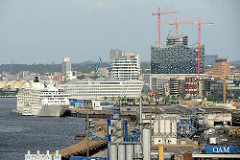 Hinter den Industrieanlagen am Kirchenpauerkai der Norderelbe die Baustelle der Elbphilharmonie - ein Kreuzfahrtschiff liegt am Hamburger Cruisecenter der Hafencity.