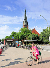 Fahrradfahrerin bei der U-Bahnstation Christuskirche - im Hintergrund der Kirche in Hamburg Eimsbüttel.
