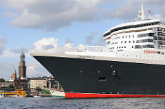 Queen Mary 2 läuft aus dem Hamburger Hafen aus  - das Passagierschiff fährt Höhe St. Pauli Landungsbrücken - an Land die Gustav Adolf Kirche und der Michel.