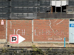 Graffiti an der Wand des Lagerschuppens am Versmannkai: "Ich liebe dich, dein Schatz"; im Vordergrund die Kaimauer und ein Hafenzeichen "Anlegen verboten".