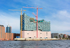 Baustelle der Elbphilharmonie in der Hafencity - Hamburgs größte Baustelle; Baukräne, blauer Himmel - Sonne, Schleierwolken.