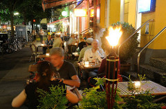 Nachtaufnahmen Hamburgs - Tische eines Restaurant stehen auf dem Bürgersteig der Gertigstrasse in Hamburg Winterhude.