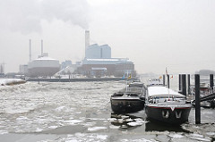 Binnenschiffe an ihrem Liegeplatz in der Billwerder Bucht - das Wasser ist mit Eisschollen bedeckt. Weisser Qualm steigt aus den Schornsteinen des Kraftwerks Tiefstack.