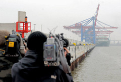 Fernsehteam beim Filmen der neuen Kaimauer am Waltershofer Hafen - Containerbrücken Burchardkai im Hamburger Nebel.