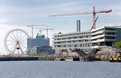 Blick aus dem Baakenhafen im Hamburger STadtteil Hafencity Richtung Magdeburger Hafen; rechts die Baustelle der HafencityUniversität und entstehende Brücke über den Baakenhafen; im Hintergrund ein Riesenrad und die Baustelle der Elbphilharmonie.