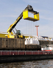 Radkran mit einer Transportvorrichtung, mit der eine Ladung von  zehn Schüttgut - Säcken an Land transportiert werden können - Fotos von der Arbeit im Hafen Hamburgs.