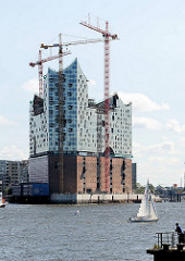 Bausstelle der Hamburger Elbphilharmonie  - ein Segelschiff kreuzt auf der Elbe.