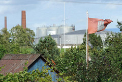 Hamburg Flagge im Kleingartengelände - Öltanks und Schornsteine einer Erdöl-Raffinerie im Harburger Seehafen.