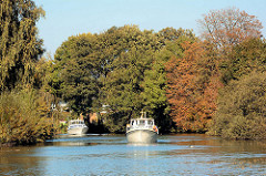 Zwei Sportboote, Motorboote auf der Dove-Elbe in den Hamburger Vierlanden / Stadtteil Curslack; die Bäume am Flussufer sind herbstlich gefärbt.