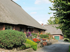 Reetdachhaus - Blumen im Vorgarten; Steinmauer aus Feldsteinen - Architektur in Hamburg GUT MOOR.