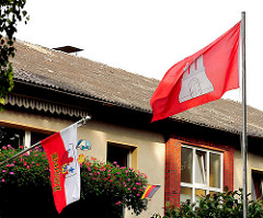 Flaggen der Hansestadt Hamburg und dem Bezirk Harburg an einem Gebäude von Hamburg Rönneburg.
