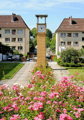 Wohnanlage Rosentreppe - blühende Rosen, Uhr auf gelber Klinkersäule - Gebäude Eisenbahn Bauverein Harburg.