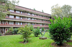 Innenhof mit Wiese und Büschen - Wohngebäude mit Laubengängen in Hamburg Dulsberg.