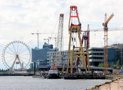 Schwimmkräne montieren ein Brückenteil der Baakenhafenbrücke am Versmannkai in der Hamburger Hafencity.