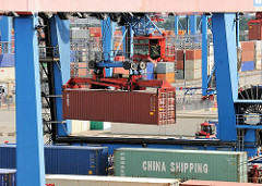 Portalkran des Containerbahnhofs auf dem Areal des Container Terminals Altenwerder - ein Container wird über den Güterwagen transportiert - in einer Kanzel sitzt der Kranführer.