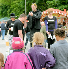 Kinder sehen einer Strassentheatergruppe bei ihrem Auftritt auf dem Hafenfest von Hamburg Harburg zu.