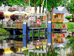 Anleger und Biergarten, Gastwirtschaft am Ernst August Kanal - Sonnenschirme und Tische im Garten am Kanalufer.