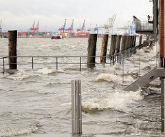 Das Hochwasser ist über die Kaimauer bei der Grossen Elbstrasse gestiegen und hat einen Fussgängersteg überschwemmt - Wellen schlagen gegen die Hauswand.