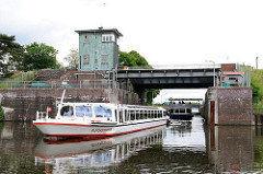 Ein Fahrgastschiff kommt aus der Krapphof Schleuse und fährt in die Doveelbe ein - im Hintergrund wartet eine weitere Barkasse und ein Sportboot auf die Ausfahrt.