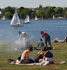 Grillspass im Sommer am Alsterufer - der Grill qualmt über die Wiese - Segelschiffe im Hintergrund.