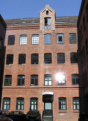 Hinterhof in Hamburg Sternschanze - historisches GEwerbegebäude aus rotem Ziegel mit Winde unter dem Dach.